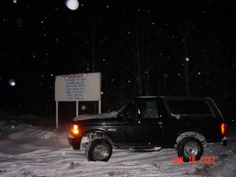 1996 Ford Bronco - A black SUV is parked in a snowy area at night, with a prominent "DANGER" sign in the background.