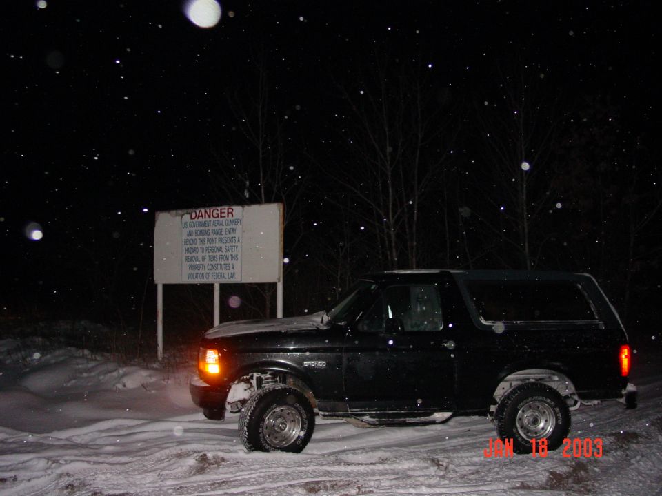Black SUV in snow at night, with a "DANGER" sign