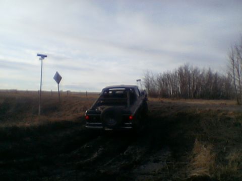 1979 Ford Bronco - 1979 Ford Bronco navigating muddy terrain with a spare tire mounted at the rear.