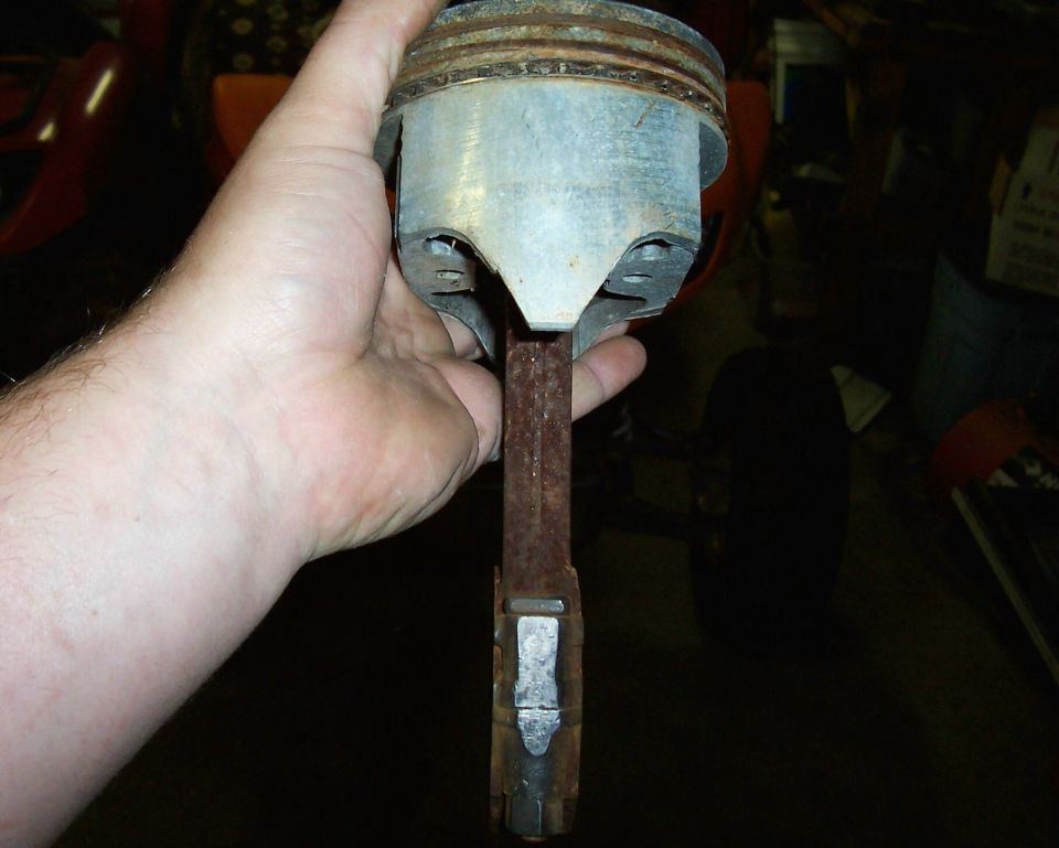 Hand holding a rusty piston and connecting rod assembly