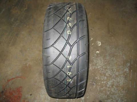 1993 Ford Probe - A close-up view of a tire with a performance tread pattern is shown resting on a concrete surface.