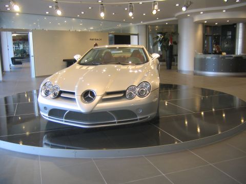 1978 Ford Bronco - A silver Mercedes-Benz SLR McLaren is displayed on a rotating platform inside a modern showroom.