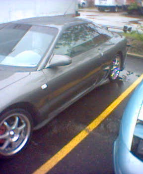 1993 Ford Probe - A dark gray coupe is parked in a lot, showing its side profile and aftermarket wheels.
