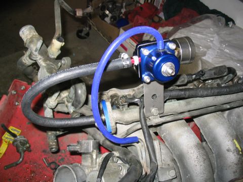 1993 Ford Probe - Close-up of engine parts including a blue fuel pressure regulator and hoses.
