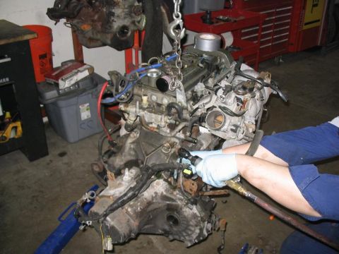 1993 Ford Probe - Mechanic works on a detached engine assembly, likely during a repair or rebuild process.