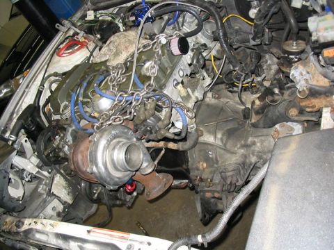 1993 Ford Probe - The engine bay is filled with custom modifications, including a large turbocharger and various hoses and wires.