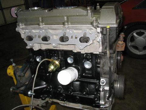 1993 Ford Probe - Engine assembly with visible parts and a partial view of a red car in the background.