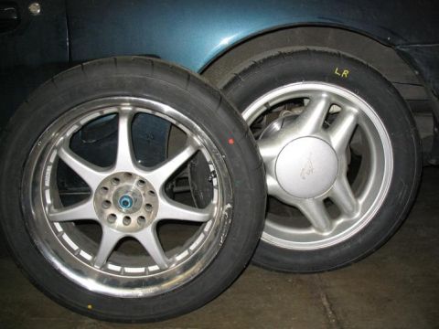 1993 Ford Probe - A close-up shows two car wheels and tires, one a Mustang emblem, against the backdrop of a dark blue vehicle.