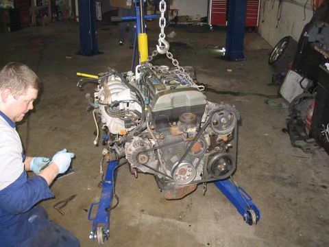 1993 Ford Probe - Engine removal in progress with a mechanic overseeing the operation.