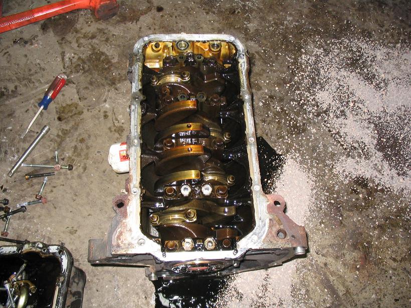 Engine block with crankshaft and oil pan removed, tools on floor