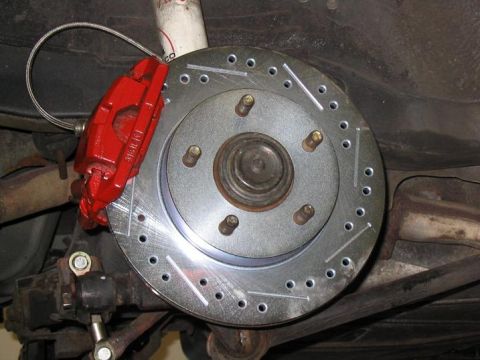 1993 Ford Probe - Close-up view of a red brake caliper and a drilled rotor, part of a vehicle's braking system.