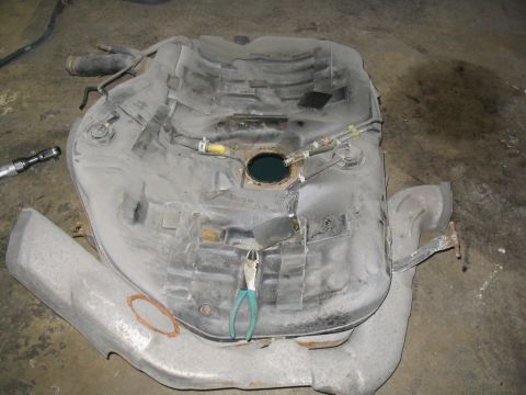 1993 Ford Probe - Fuel tank removed from a vehicle, with tools present.