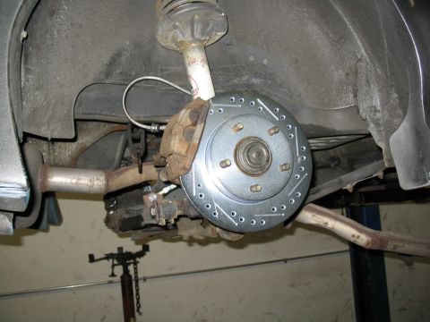 1993 Ford Probe - Close-up view of a vehicle's rear brake assembly, a newly installed drilled brake rotor and caliper.