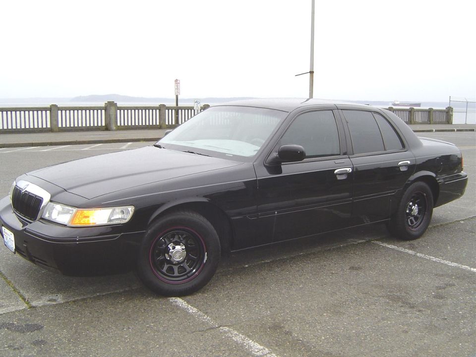 Black Mercury Grand Marquis sedan with black steel wheels by the waterfront