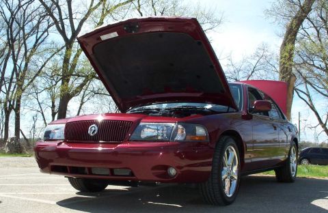 1998 Ford Crown Victoria - A red Mercury Grand Marquis is parked outside with its hood and trunk open, revealing the engine bay and interior.
