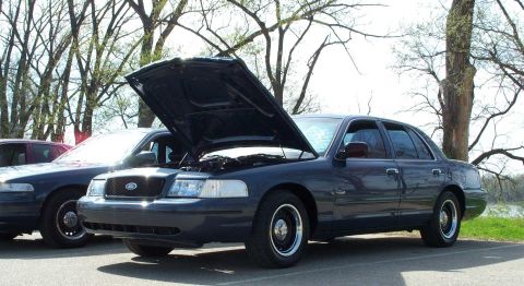 1998 Ford Crown Victoria - A dark blue sedan, likely a 2003 model, is parked with its hood open, revealing the engine compartment.