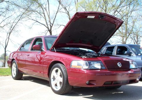 1998 Ford Crown Victoria - A red 1998 Ford Crown Victoria is parked with its hood open, showing the engine bay.