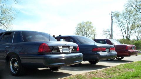 1998 Ford Crown Victoria - Three Ford Crown Victorias parked in a lot on a sunny day.