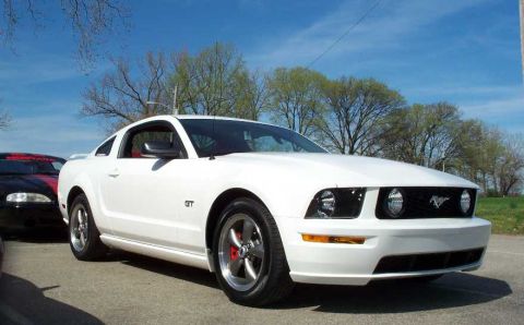 1998 Ford Crown Victoria - A white Ford Mustang GT is parked outside on a sunny day, with another vehicle visible to its left.