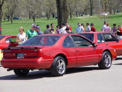 1998 Ford Crown Victoria - Red coupe seen at an outdoor car event with spectators in the background.