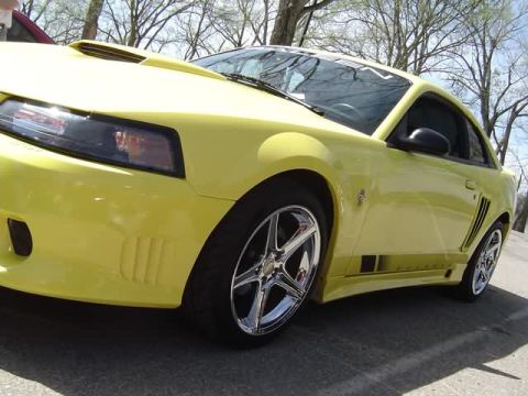 1998 Ford Crown Victoria - This yellow coupe features a distinctive hood scoop and side stripe, captured in a low 3/4 front view.