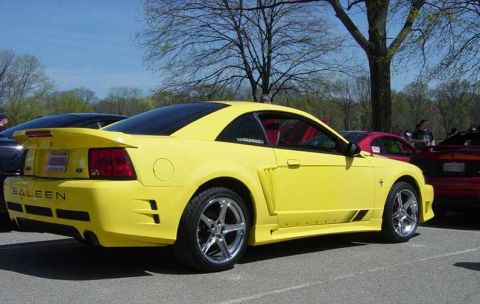 1998 Ford Crown Victoria - A bright yellow Saleen Mustang is parked at a car show, with other vehicles visible in the background.