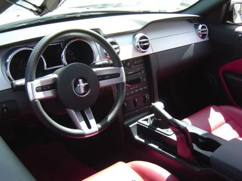 1998 Ford Crown Victoria - The interior of a modern car features red seats and a dashboard with a prominent Mustang emblem on the steering wheel.