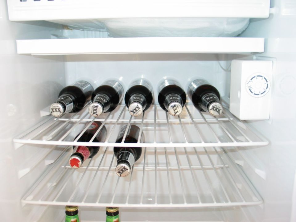 Bottles of beer on refrigerator shelves, some with XXX caps