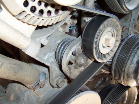 1994 Ford F-150 - A close-up view of the engine's belt system, focusing on the tensioner and pulleys.
