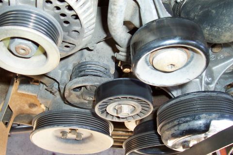 1994 Ford F-150 - Close-up of engine pulleys and belts, showing various ribbed and smooth surfaces.