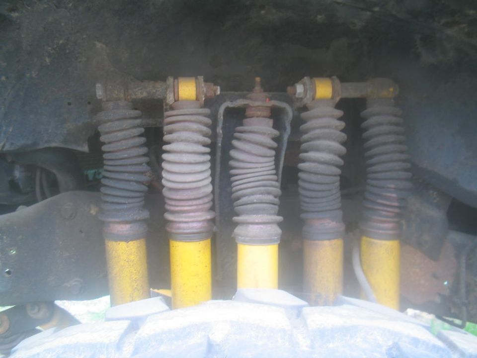 Five yellow shock absorbers with gray bellows, viewed from below