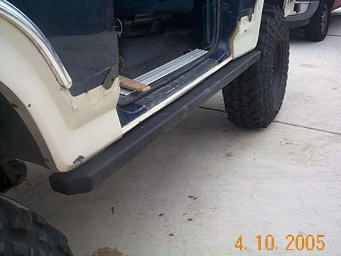 1986 Ford Bronco - Side view of a 1986 Ford Bronco with the door open, revealing the interior and a slider step.