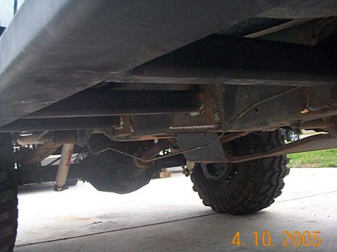 1986 Ford Bronco - The undercarriage of a 4x4 vehicle is visible, large tires and suspension components.