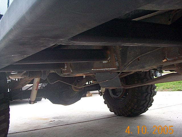 Under-side view of lifted truck frame, rear axle, white shock and mud tire, dated 4.10.2005