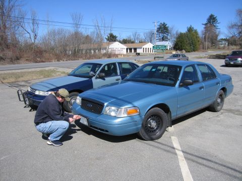 1991 Ford LTD Crown Victoria - A person is attending to the front of a blue Ford Crown Victoria, with another car parked behind it.