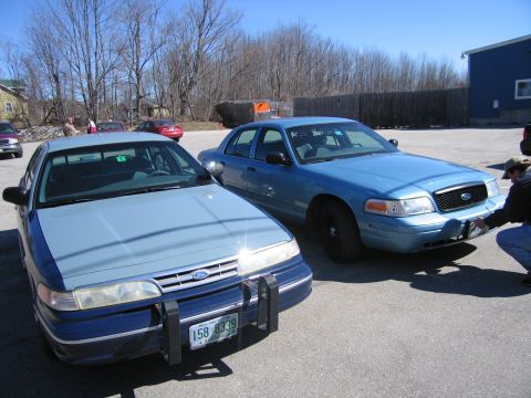 1991 Ford LTD Crown Victoria - Two Ford Crown Victorias are parked in a lot under a clear blue sky.