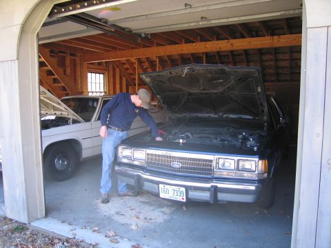 1991 Ford LTD Crown Victoria - A man works on the engine of a 1991 Ford Crown Victoria LTD parked in a garage next to another vehicle.