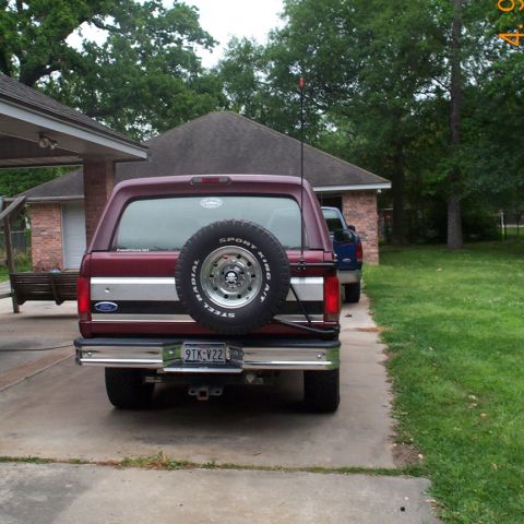 1996 Ford Bronco - Rear view of a maroon 1996 Ford Bronco parked in a driveway, showing its spare tire and license plate.