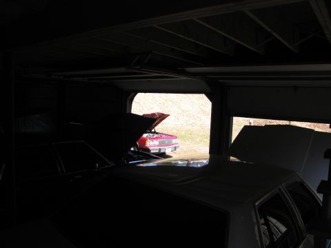 1991 Ford LTD Crown Victoria - Two vehicles are partially visible inside a dark garage, with one red sedan parked outside.