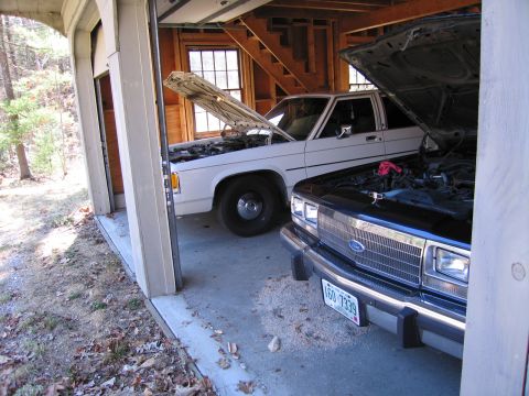 1991 Ford LTD Crown Victoria - Two cars, a 1991 Ford Crown Victoria LTD and another vehicle, are parked in a garage with their hoods open.