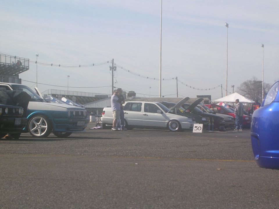 White sedan with hood open at a car show, number 50 visible