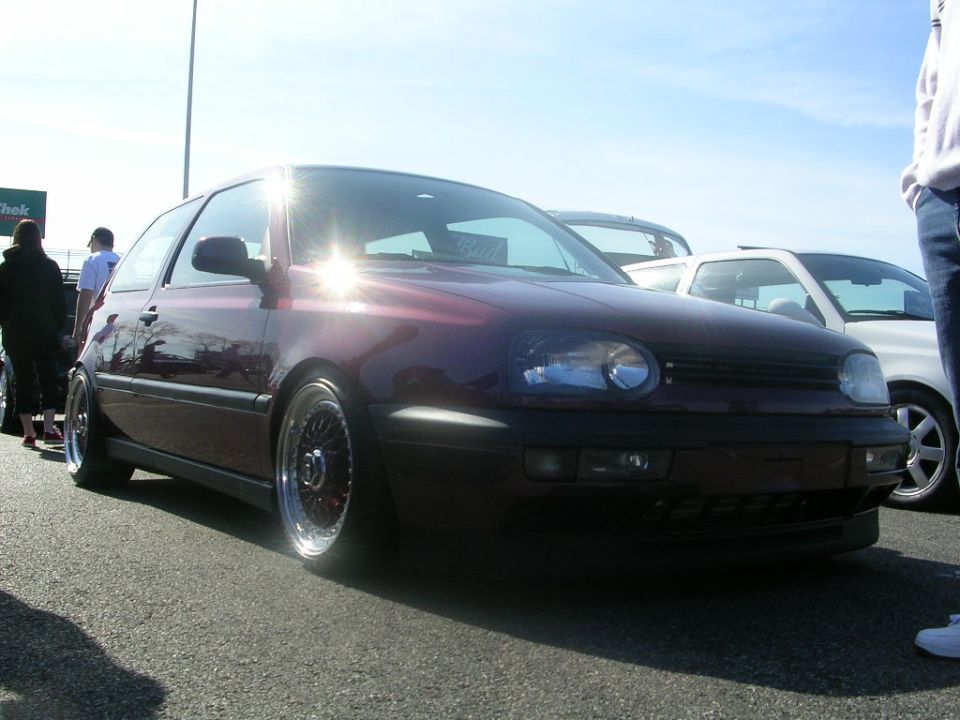 Maroon Volkswagen Golf Mk3 with aftermarket wheels, parked next to a white car