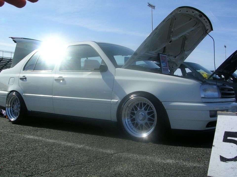 White sedan with hood open, lowered on BBS-style wheels. Visible text: SUPERMOTORS.NET