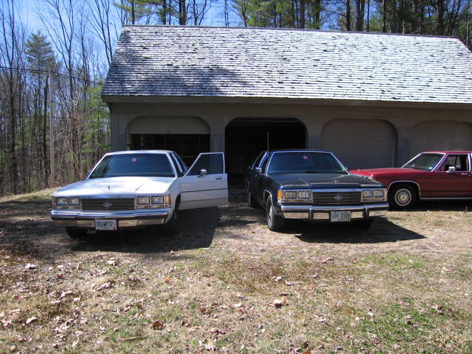 White 1988 Ford Crown Victoria with driver's door open, parked in front of a garage