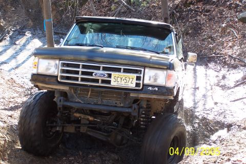 1979 Ford Bronco - A black Ford truck navigates a challenging muddy off-road course.