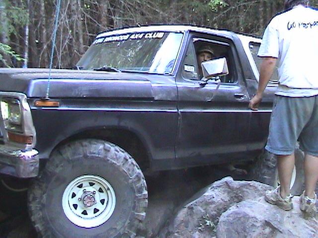 Dark 1978 Ford Bronco 4x4 off-roading over rocks