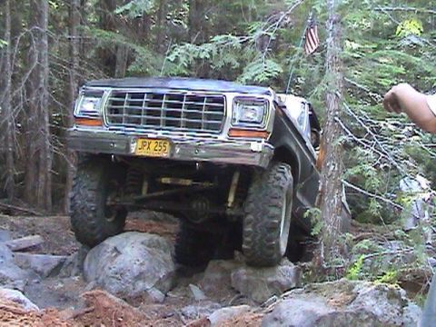1978 Ford Bronco - This 1978 Ford Bronco is shown off-roading over large rocks in a wooded area.