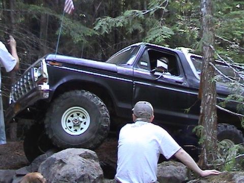 1978 Ford Bronco - A 1978 Ford Bronco navigates a rocky obstacle on a forest trail.