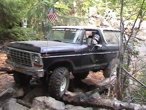 1978 Ford Bronco - This 1978 Ford Bronco is tackling a challenging off-road trail with large rocks and trees.
