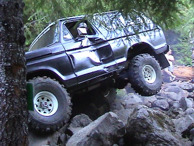 Dark 1978 Ford Bronco climbing over rocks on a trail